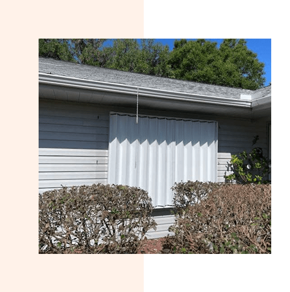 Storm shutters cover a residential window, protecting the house.