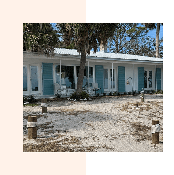 A row of blue beach cabins under palm trees on a sunny day.