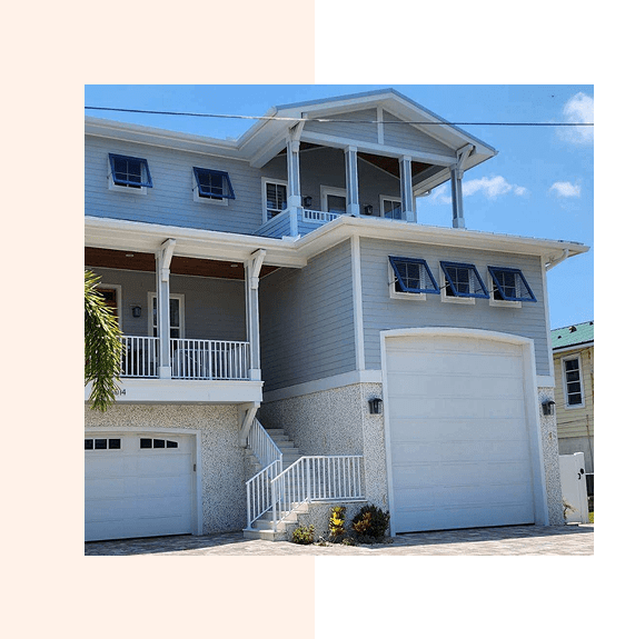 A modern, two-story house with a garage and balcony under a clear blue sky.