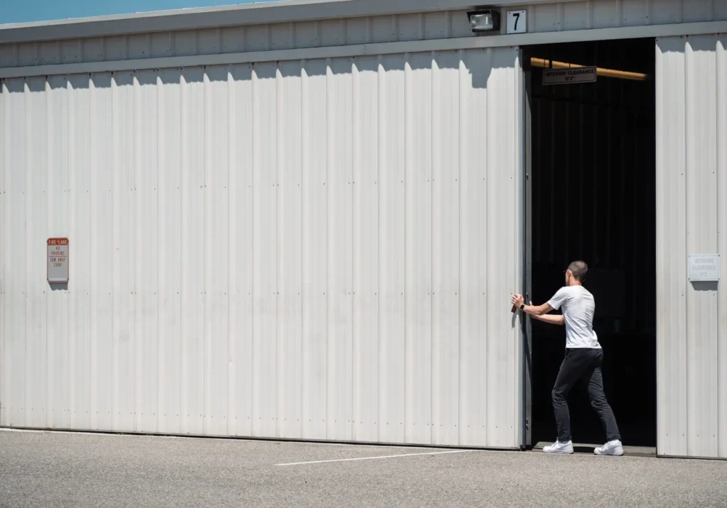 Person opening large white garage door.