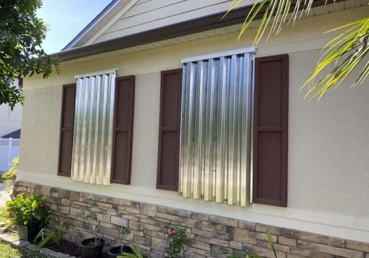 House windows protected by metal hurricane shutters