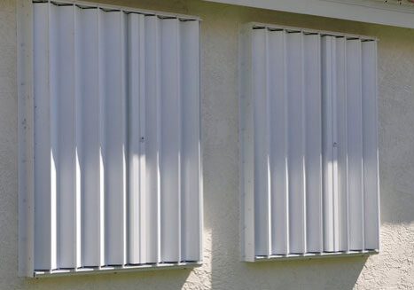 Metal shutters covering two windows outside.